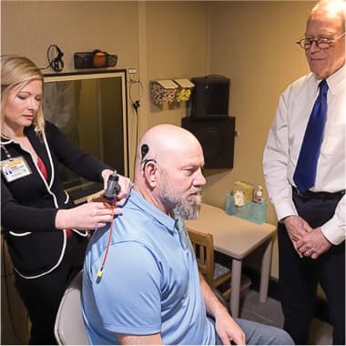 Two medical employees working with a seated patient