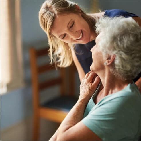 An elderly woman interacting with a smiling nurse