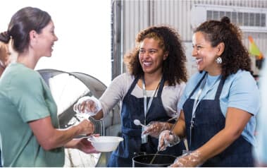 Two women serving another woman with smiles on their faces