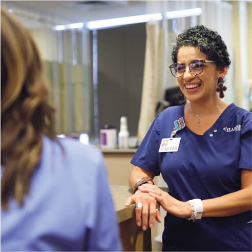 A female nurse smiling while leaning onto a counter