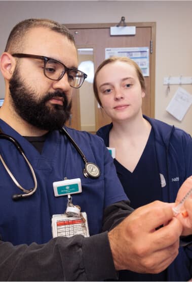 A male and female nurse looking at a syringe