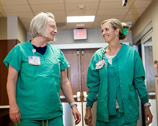 Two female nurses having a joyful conversation in the hallway